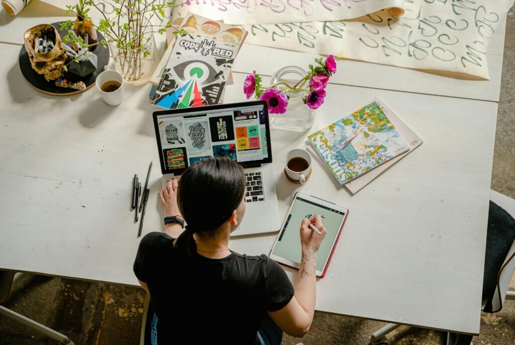 Artistic workspace featuring calligraphy and digital design on a tablet and laptop.